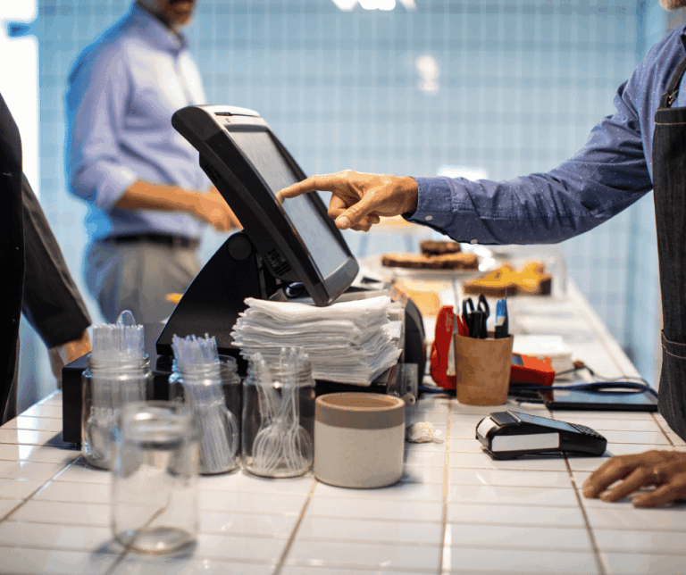 Café counter with a touchscreen POS terminal and separate card reader in use